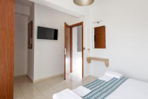 a white room with a bed and a television at Private Rooftop Jacuzzi Sea View Walk to Beach in Rethymno