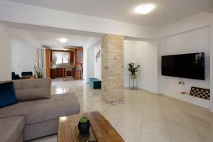 Amaltheia Luxury Residence في مدينة ريثيمنو: غرفة معيشة مع أريكة وتلفزيون على الحائط