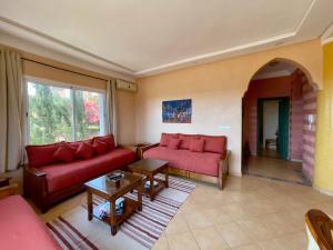 a living room with two red couches and a table at A7 Maison Blanche Imi ouaddar in Agadir