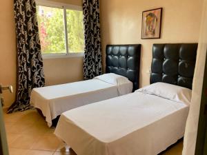 two beds in a room with a window at A7 Maison Blanche Imi ouaddar in Agadir