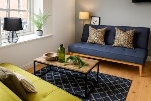 a living room with a blue couch and a table at Morpeth City Centre Apartment in Morpeth
