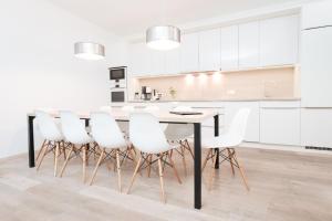 a white kitchen with a table and white chairs at Sport Chalet Maria Alm in Maria Alm am Steinernen Meer