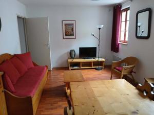 a living room with a red couch and a table at Charmant 2 Pièces pour 6 Personnes avec Piscine à Vignec, Proche Saint-Lary-Soulan - FR-1-504-101 in Vignec