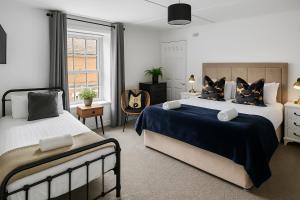 a bedroom with two beds and a chair at Morpeth City Centre Apartment in Morpeth
