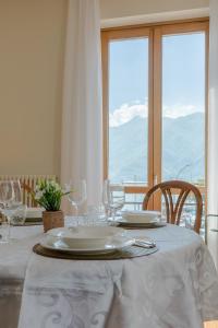 a white table with plates and glasses and a window at Casa MAMMA in Lovere