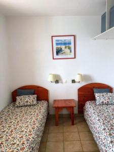 una habitación de hotel con dos camas y una mesa en Appt T4 Résidence Le Cordouan 3 étoiles côté Piscine, en Soulac-sur-Mer 11 fotos más