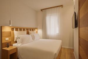 a bedroom with a large white bed and a television at Hotel Le Mura in Lazise