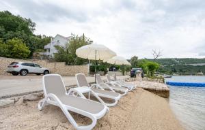 a row of white chairs and umbrellas on a beach at Apartman Marija Slano by Villas Guide in Slano