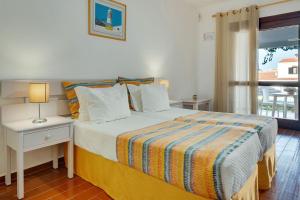 a bedroom with a bed with a nightstand and a window at Muthu Balaia Sol in Albufeira