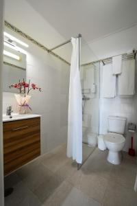 a white bathroom with a toilet and a sink at Muthu Balaia Sol in Albufeira +43 photos