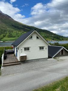 a white building with a wooden ramp next to a road at Sea Front Olden in Olden