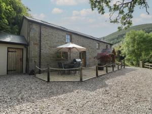 纽波特Graig Cottage的前面有桌子和雨伞的建筑