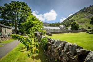a stone wall in front of a green field at Nant Gwrtheyrn in Llithfaen