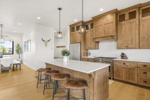 a kitchen with wooden cabinets and a island with bar stools at Rare Fall Dates Hot Tub & Game Room Dogs in Driggs