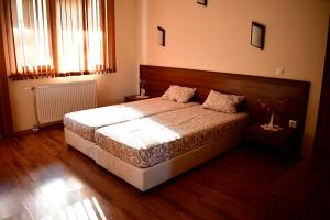 a bedroom with a bed with a wooden headboard at Семеен Хотел Ажур in Kotel