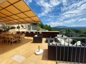 a patio with a table and chairs on a deck at Le Point Sublime – Villa de Charme à Vaison la Romaine in Vaison-la-Romaine