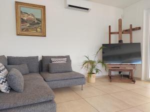 a living room with a couch and a flat screen tv at Le Point Sublime – Villa de Charme à Vaison la Romaine in Vaison-la-Romaine