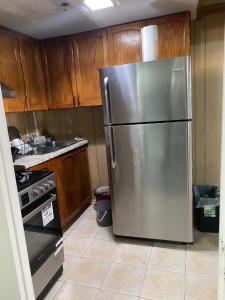 a stainless steel refrigerator in a kitchen with wooden cabinets at Peace and Comfort 1-bedroom basement Apartment in Brampton