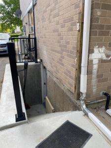 a corner of a building with a brick wall and a grate at Peace and Comfort 1-bedroom basement Apartment in Brampton