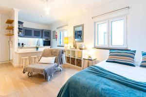 a bedroom with a bed and a chair and a kitchen at Beco dos Inválidos 67 Apartments in Cascais