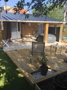 a wooden deck with a chair and a table at Studio à 50M de la mer avec SPA in Grandcamp-Maisy