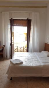 a bedroom with a large white bed with a window at Hotel Al Sogno in Alassio