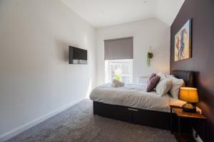 een slaapkamer met een bed met een lamp en een raam bij The Bishops Nest in Bishop Auckland