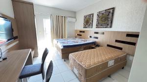 a small room with two beds and a table and a desk at Apartamentos Lagoa Quente Hotel in Caldas Novas +20 photos