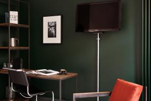 a room with a desk with a television on a green wall at Gastwerk Hotel Hamburg in Hamburg