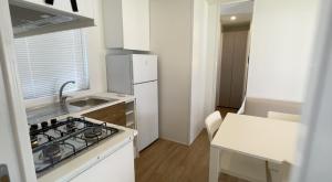 Una pequeña cocina con estufa y refrigerador. en Höffmann Bungalowpark Baia Domizia - Village Baia Domizia, en Baia Domizia 5 fotos más