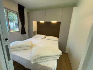 Un dormitorio con dos camas con sábanas blancas y una ventana en Höffmann Bungalowpark Baia Domizia - Village Baia Domizia, en Baia Domizia