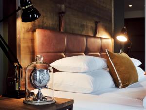 a clock sitting on a table next to a bed at Gastwerk Hotel Hamburg in Hamburg