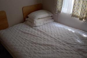 Una cama con sábanas blancas y almohadas. en Comfortable family caravan in Weymouth, en Weymouth