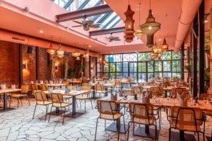 a dining room with tables and chairs and windows at Gastwerk Hotel Hamburg in Hamburg