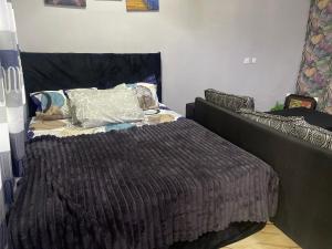 a bed with a brown comforter in a bedroom at Skl apartment in Adentan