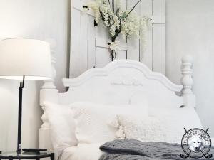 ein weißes Schlafzimmer mit einem weißen Bett und einer Vase aus Blumen in der Unterkunft WHITE WOLF Farmhouse Retreat in Reidsville