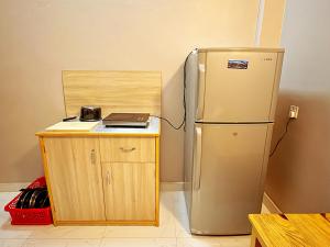 a kitchen with a refrigerator and a wooden cabinet at Amigo Studio Inn Pokhara in Pokhara