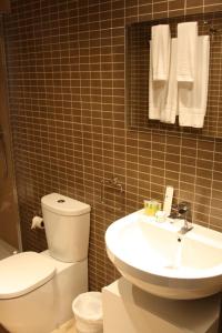 a bathroom with a toilet and a sink and towels at Apartamentos Poniente - Mares in Torre del Mar