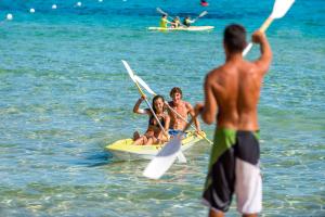 a group of people on a paddle boat in the water at Chia Laguna - Hotel Village in Chia