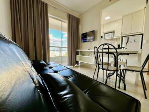 a living room with a black leather couch and a table at Apartamentos Recanto do Bosque in Caldas Novas