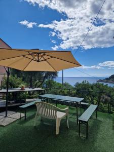 a patio with a table and a bench and an umbrella at Il Paradiso di Adriana in Bonassola