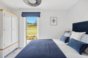 a bedroom with a bed with blue pillows and a window at No 2 The Vista, Willingcott, Woolacombe in Woolacombe +29 photos