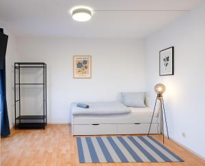 Una habitación blanca con una cama y una alfombra azul. en StayInn Halle (Saale), en Nietleben