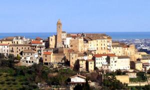 a group of buildings on a hill with a clock tower at Spineola in Spinetoli