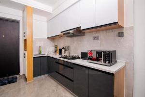 Una cocina con gabinetes negros y un horno de estufa. en Faith Ajema, en Nairobi 2 fotos más