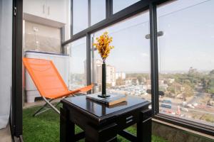 Una silla naranja y una mesa con un jarrón encima. en Faith Ajema, en Nairobi