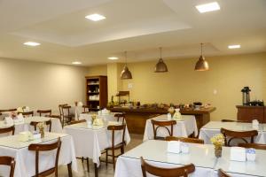 ein Esszimmer mit weißen Tischen und Stühlen in der Unterkunft Hotel Milenio in Ponte Nova