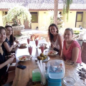 a group of women sitting around a wooden table at Bonsai Guesthouse Banyuwangi in Banyuwangi