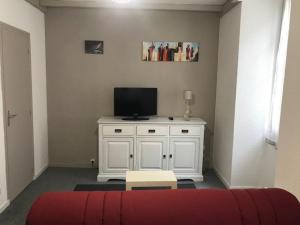 a living room with a tv and a white cabinet at La SOURCE FROIDE in Eaux-Bonnes