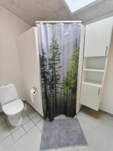 a bathroom with a shower curtain with a forest at Riverview Cottage in Randbøl